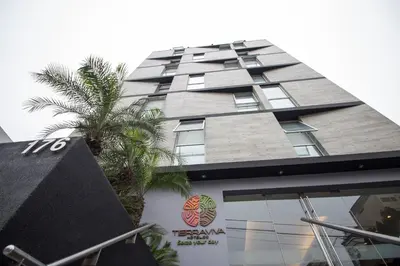 a tall building with a palm tree in front of it at Tierra Viva Miraflores Larco in Lima