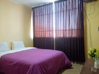 a bedroom with a purple bed and a large window at CasaHotel Centro - Huancayo in Huancayo