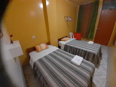 two beds in a room with yellow walls at Nasca Trails B&B in Nazca