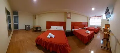a bedroom with two beds with red sheets at Lembranças Hotel in Huánuco