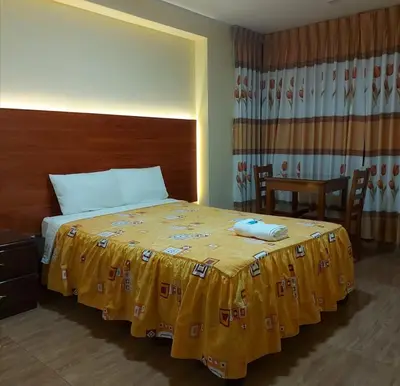 a bedroom with a bed with a yellow blanket on it at Lembranças Hotel in Huánuco
