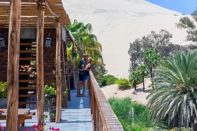 a couple standing on a wooden walkway near the beach at Banana's Adventure Hostel in Ica
