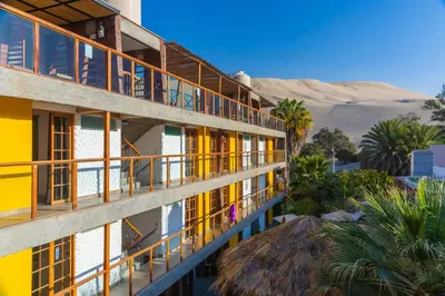 a building with colorful balconies with the desert in the background at Banana's Adventure Hostel in Ica