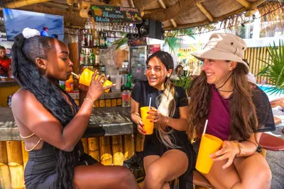 three women sitting at a bar drinking orange juice at Banana's Adventure Hostel in Ica