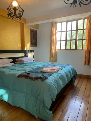 a bedroom with a large bed with a blue comforter at Qolqampata Hotel in Cusco
