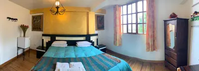 a bedroom with a bed and two chairs in it at Qolqampata Hotel in Cusco