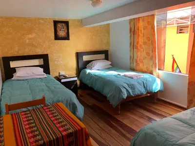 a hotel room with two beds and a window at Qolqampata Hotel in Cusco