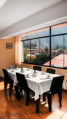 a dining room with tables and chairs and large windows at Hotel Andes Urubamba in Urubamba