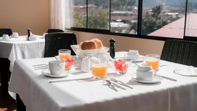 a table with a white table cloth with breakfast foods on it at Hotel Andes Urubamba in Urubamba