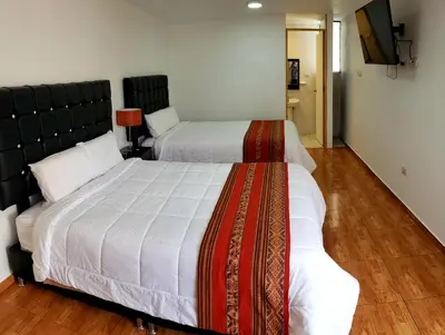 a bedroom with two beds and a flat screen tv at Cusco de mis Sueños in Cusco