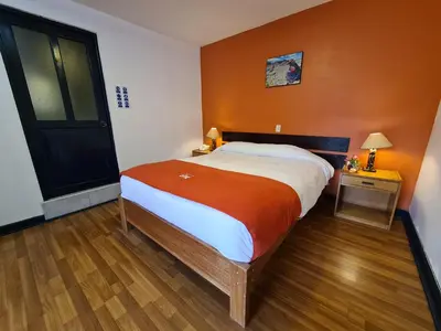 a bedroom with a large bed with an orange wall at Hotel Casa Campesina in Cusco