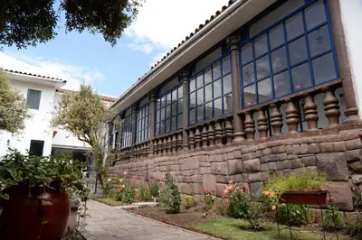a brick building with large windows and some plants at La Casa de Fray Bartolome in Cusco