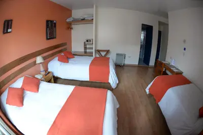 a room with two beds with orange and white at La Casa de Fray Bartolome in Cusco