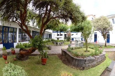 a garden with a tree and tables and chairs at La Casa de Fray Bartolome in Cusco