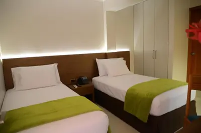 a hotel room with two beds with green sheets at Hotel Monte Cafeto INN in Pichanaki