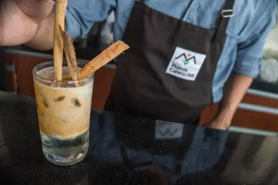 a person in apron making a drink with cinnamon sticks at Hotel Monte Cafeto INN in Pichanaki