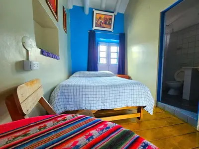 a bedroom with a bed and a bathroom with a window at Hospedaje Euro's De San Blas in Cusco