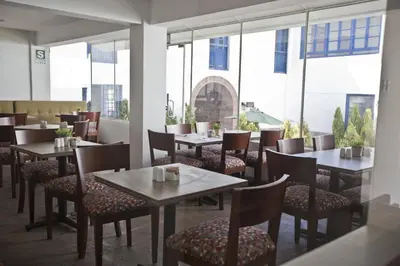 a restaurant with tables and chairs and large windows at Tierra Viva Cusco Centro in Cusco