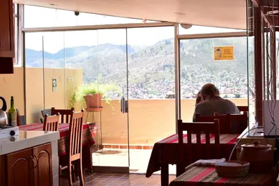 a man sitting at a table looking out of a window at Kuska Hostal in Cusco