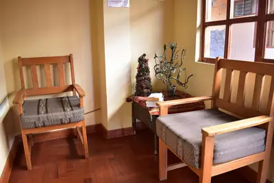 a room with two wooden chairs and a window at Kuska Hostal in Cusco