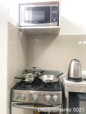 a kitchen with a stove with two pots and a microwave at Departamento Miraflores in Lima