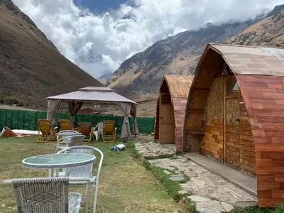 a table and chairs in front of a small building at Soraypampa Hostel - Private Cabins & Dorms for Self-Guided Humantay & Salkantay Trek -Comidas-hot shower-wifi-Pack horses in Salcantay