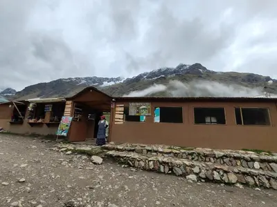 a house with smoke coming out of it with a mountain at Soraypampa Hostel - Private Cabins & Dorms for Self-Guided Humantay & Salkantay Trek -Comidas-hot shower-wifi-Pack horses in Salcantay