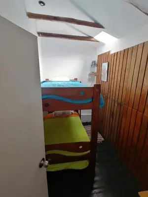 a bedroom with a bunk bed in a room with a door at Asiriq Wasi Guest House in Cusco