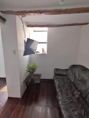 a living room with a leather couch and a window at Asiriq Wasi Guest House in Cusco
