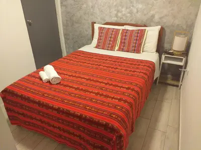 a bed with a red blanket and two pillows at Chakana Family Home Lima Airport in Lima
