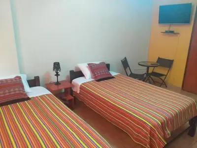 two beds in a room with a table and chairs at Chakana Family Home Lima Airport in Lima