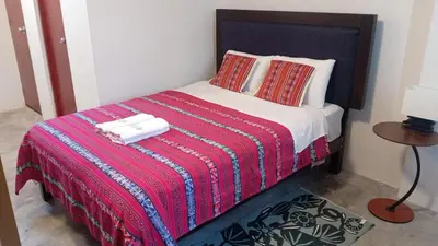 a bedroom with a bed with a red blanket and a table at Chakana Family Home Lima Airport in Lima