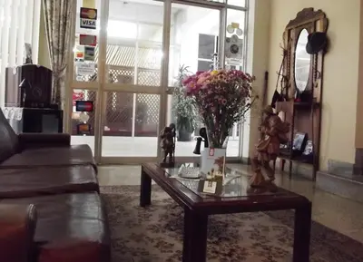 a living room with a table with a vase of flowers on it at Hostal Gemina in Lima