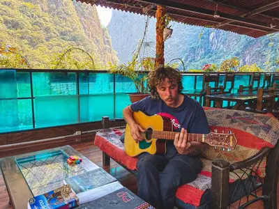 a man sitting on a chair playing a guitar at Nativus Hostel Machu Picchu in Machu Picchu