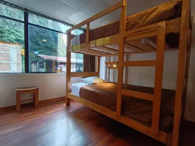 a bedroom with two bunk beds and a large window at Nativus Hostel Machu Picchu in Machu Picchu
