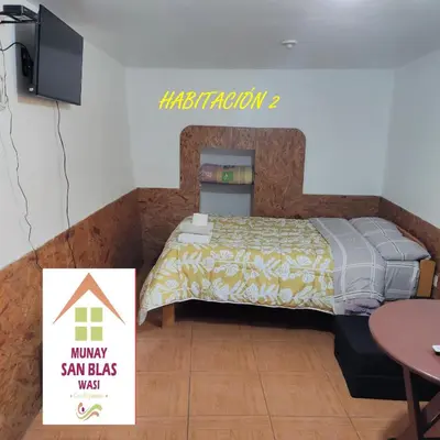 a bedroom with a bed with a tv and a table at Munay San Blas Wasi in Cusco