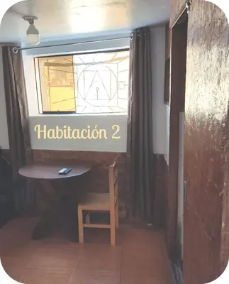 a table and a chair in a room with a window at Munay San Blas Wasi in Cusco