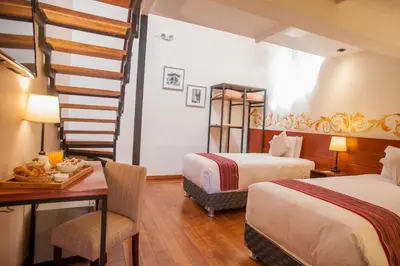 a hotel room with two beds and a desk and a staircase at Casa Biru Hotel Boutique in Cusco