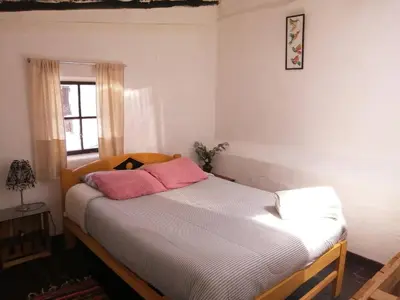 a bedroom with a bed with pink pillows on it at Asiriq Wasi Casita de huéspedes in Cusco