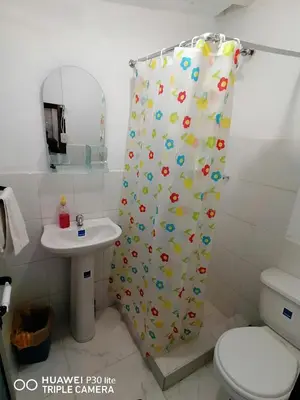 a bathroom with a shower curtain with a toilet and a sink at Asiriq Wasi Casita de huéspedes in Cusco
