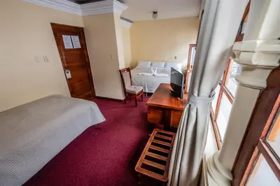 a bedroom with a bed and a desk with a television at Hostal El Peregrino in Cusco