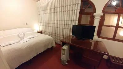 a bedroom with a bed and a desk with a television at Hostal El Peregrino in Cusco