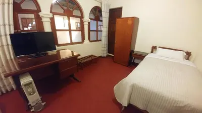 a bedroom with a bed and a desk with a television at Hostal El Peregrino in Cusco
