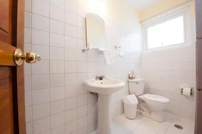 a white bathroom with a sink and a toilet at Hostal El Peregrino in Cusco