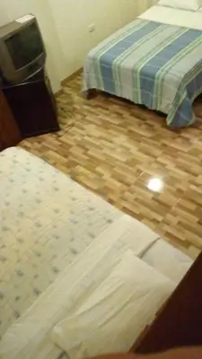 a bedroom with two beds and a wooden floor at Posada Gino in Pisco
