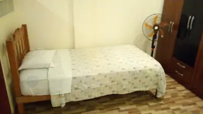 a small bed in a bedroom with a fan at Posada Gino in Pisco