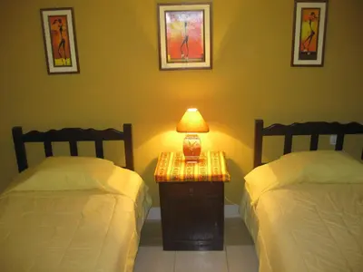a bedroom with two beds and a lamp on a table at Posada Gino in Pisco