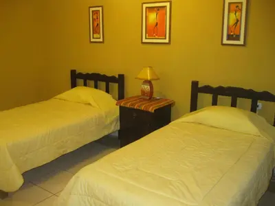 a bedroom with two beds and a table with a lamp at Posada Gino in Pisco