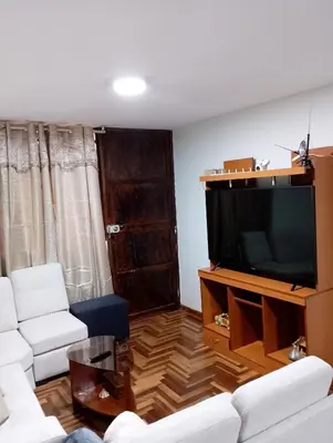 a living room with a couch and a television at MUNAYCHA`S WASI in Cusco
