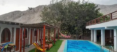 a house with a swimming pool in front of a mountain at Hotel Quilla Wasi in Lunahuaná